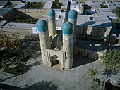 Aerial view of Chor Minor Madrasah's striking turquoise domes rising against the weathered brick, embraced by the city's ancient architecture, Buxoro, Buxoro Viloyati, Uzbekistan.