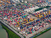 Luftaufnahme eines Kaleidoskops von gestapelten Schiffscontainern in einem geschäftigen Hafen, in dem der Handel auf das Meer trifft, im Jawaharlal Nehru Port Trust (JNPT) in Navi Mumbai, Indien