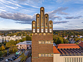 Aerial view of the Hochzeitsturm's unique architecture standing tall against a backdrop of autumnal foliage and a soft, cloud-strewn sky, Darmstadt, Hessen, Germany.