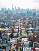 Aerial view of a long street bisecting dense buildings, runners in the New York Marathon in front of a distant skyline shrouded in a soft, hazy atmosphere, Brooklyn, New York, United States.