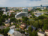 Aerial view of modern glass buildings rise amidst the historic charm of Snipiskes, bordered by verdant trees and the winding river, Vilnius, Vilnius, Lithuania.
