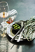 Place setting with olive branches, green olives, amber wine