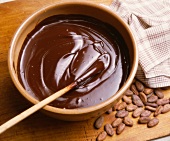 Schüssel mit geschmolzener Schokolade, daneben Kakaobohnen