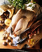 Rohes Hühnchen mit Zutaten für die Füllung: Speck, Maronen, Zwiebeln