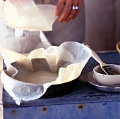 A round cake tin being lined with brick pastry