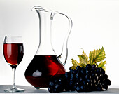 Rotwein in Glas und Karaffe, blaue Weintrauben