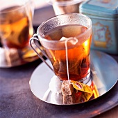 Zwei Glastassen Tee mit Teebeutel und Würfelzucker