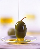 Grüne Olive wird mit Olivenöl beträufelt