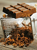 Dunkle Schokolade auf einer Küchenreibe mit geraspelter Schokolade