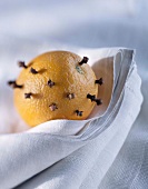 Mit Nelken gespickte Orange auf weißem Küchentuch