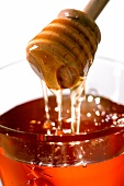 Honiglöffel mit fliessendem Honig und Honigglas