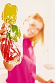 A girl holding colourful peppers in a plastic bag