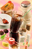 Symbolbild Zucker: Zuckerhaltiges Getränk, Zucker und verschiedene Süssigkeiten