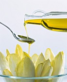 Olivenöl mit Löffel über Chicorée träufeln