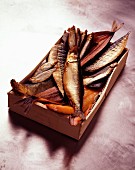 Holzkiste mit verschiedenen Räucherfischen