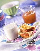 Breakfast with glass of milk, bread and apricot jam