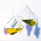 Zwei an Schnüren hängende Glasbecher mit Walnuss- und süssem Mandelöl