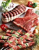 Stillleben vom Rindfleisch: Filetbraten, T-Bone-Steaks, Fleischspiesse, Gemüse und Würzzutaten