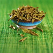 Dragon Well tea (Chinese green tea) in bowl on green mat
