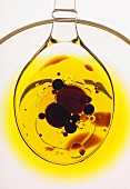 Olivenöl und Tropfen von Balsamicoessig auf transparentem Löffel