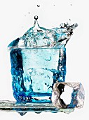 Eiswürfel fallen in ein Glas Wasser