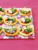 Mini-Pizzas mit Rucola, Parmesan und Pinienkernen