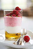 Layered dessert with honey, raspberry and cream cheese in a glass