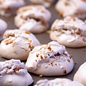 Meringues with crushed hazelnuts on baking tray