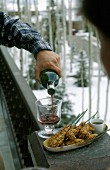 Garnelenspiesse auf Teller, Mann schenkt Rotwein ein
