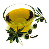 Schälchen mit Olivenöl, schwarze Oliven und kleine Olivenzweige