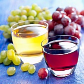 Rotwein und Weißwein in Gläsern, Trauben im Hintergrund