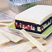 A square cake made from white and dark chocolate with fruits of the forest