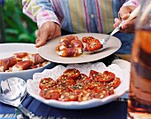 Mann serviert eingelegte Tomaten und Parmaschinkenröllchen mit Ziegenkäse