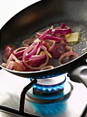 Cooking red onions in a frying pan