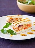A layered cake with grilled fish and tomato pilau