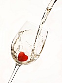Weißwein wird in ein Glas mit Herz-Eiswürfel gegossen