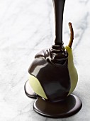 Schokoladensauce wird über eine geschälte Birne gegossen