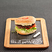 Hamburger with lettuce, tomato and cream cheese on a chalkboard
