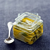 Square jar of marinated chicory with herbs