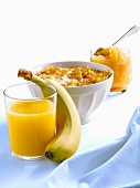 Frühstück mit Orangensaft, Banane, Cornflakes in Milch und Kompott