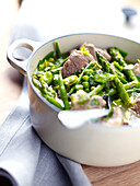 Casserole dish of lamb and green vegetables