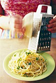 Grating cheese on a plate of spaghetti