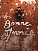 Schriftzug Bonne Année in Kakaopulver und Schälchen mit Schokotrüffel