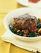 Thick piece of beef marinated with mustard, spinach with pine nuts and raisins