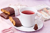 Cup of red tea with chocolate coated cookies