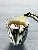 Grüner Tee wird in Tasse gegossen