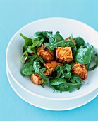 Pan-fried salmon cubes with spinach and rocket lettuce salad
