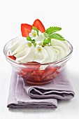 Organic strawberry fruit salad with whipped cream and decorated with wild strawberry flowers