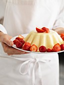 Person holding a plate of entremets with strawberries and raspberries