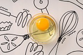 Rohes Ei in einem Glasschälchen auf Backutensilien-Illustration